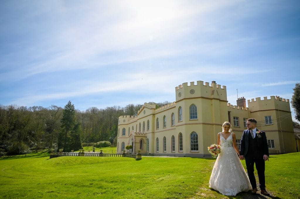 a man and woman in a wedding dress in front of a castle