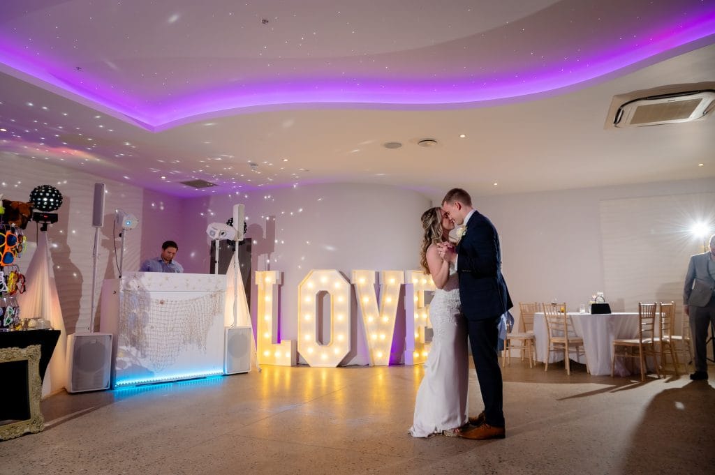 a man and woman kissing in a room with a table and chairs