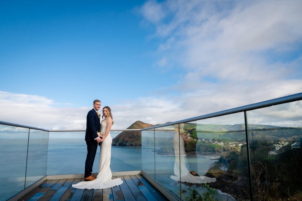 a man and woman posing for a picture on a balcony overlooking water