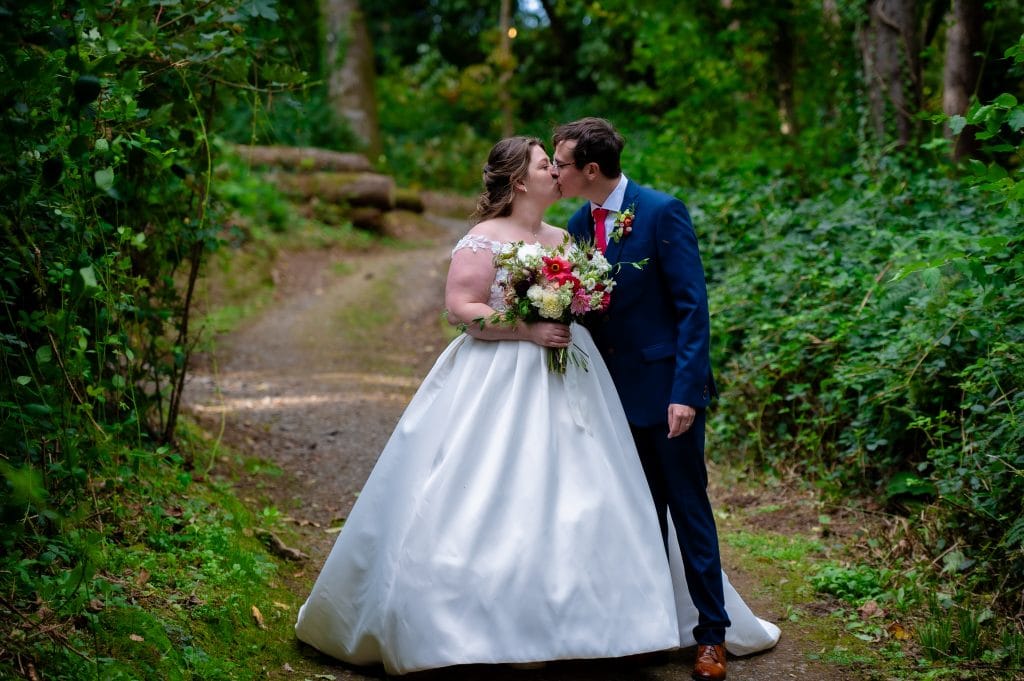 a man and woman kissing on a path in the woods