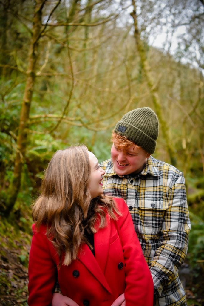 a man and woman smiling in the woods