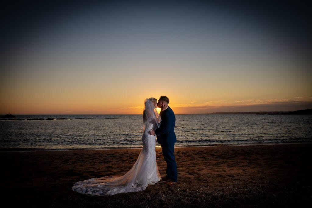a man and woman kissing on a beach