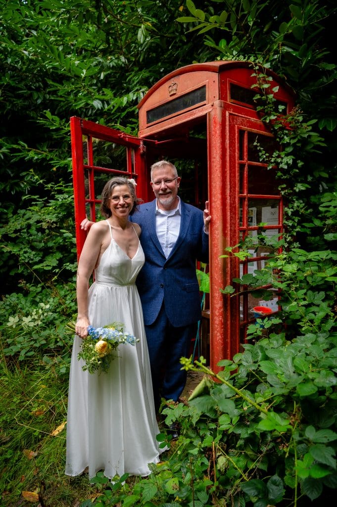 a man and woman standing in a red phone booth
