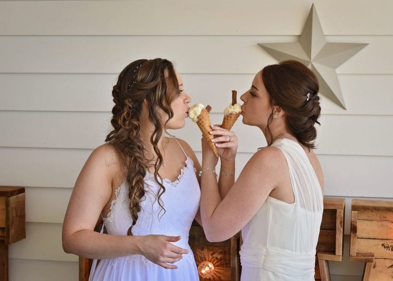 two women in white dresses eating ice cream