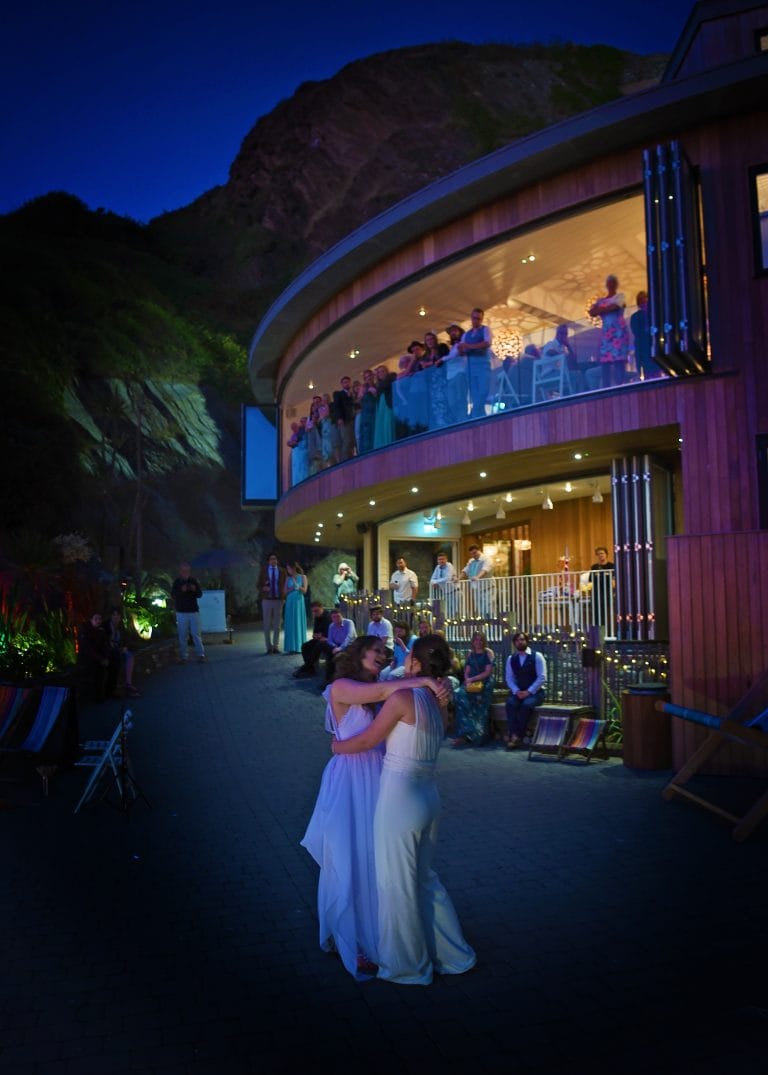 two women in white dresses dancing outside of a building