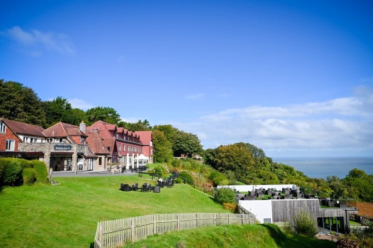 a building with a fence and chairs on a hill
